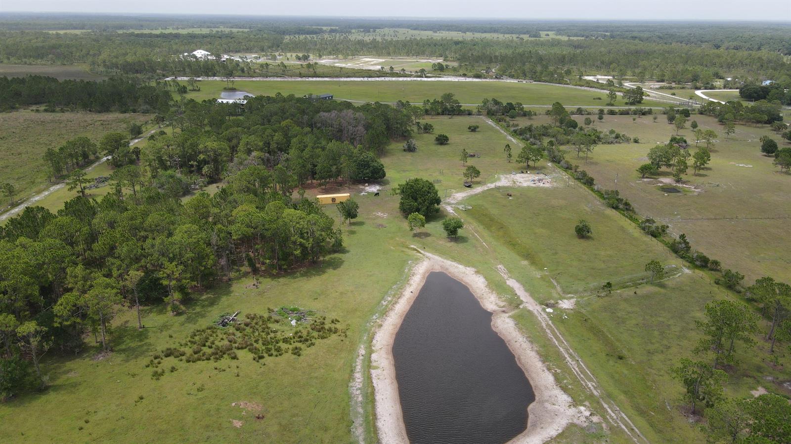 An aerial view shows a rural property with a pond, scattered trees, and a shipping container — 12271 NE 124th Avenue, Okeechobee FL 34972, OKEECHOBEE, FL