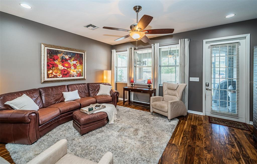 A living room features a brown leather sectional, a beige armchair, and dark wood flooring — 3515 ALBRITTON STREET, NEW PORT RICHEY, FL