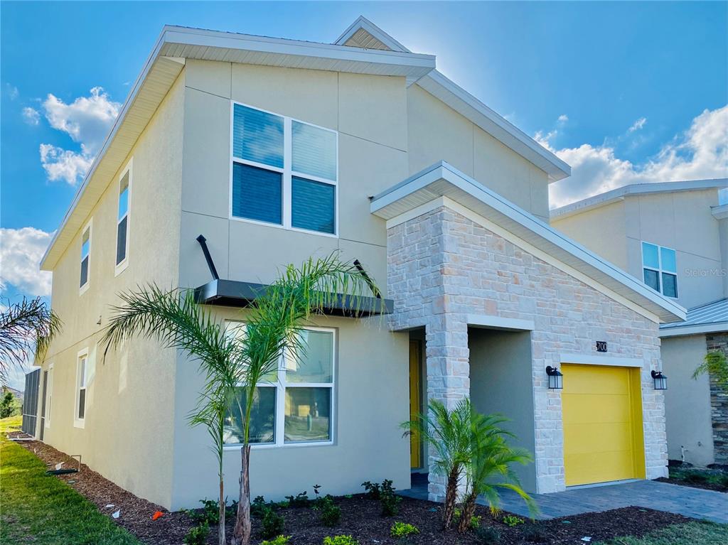 A two-story house with a yellow garage door and stone facade under a blue sky — 700 WHISTLING STRAITS BOULEVARD, DAVENPORT, FL