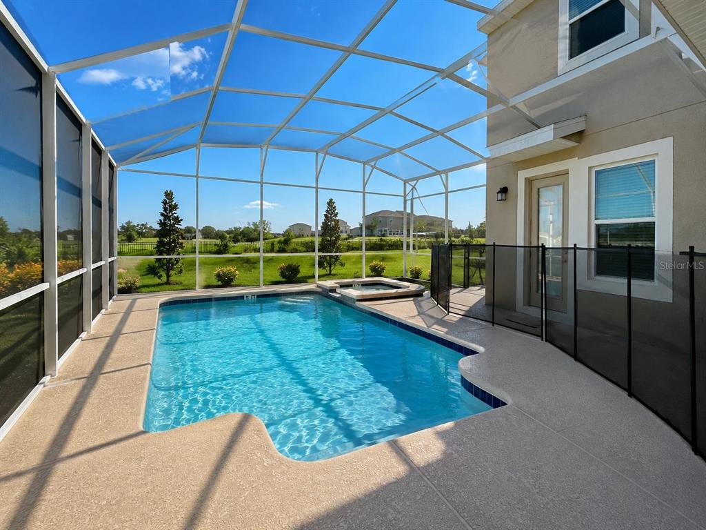 A screened-in swimming pool and spa sit on a patio behind a two-story house — 700 WHISTLING STRAITS BOULEVARD, DAVENPORT, FL
