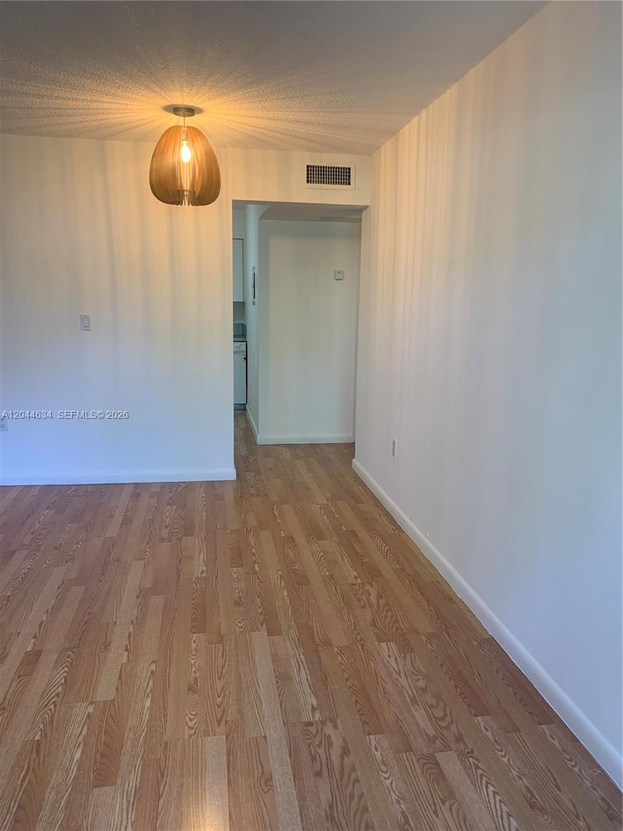 A room with light wood-look flooring, white walls, and a modern wooden pendant light fixture — 2460 SW 18th Ave # 1205, Miami FL 33145, MIAMI, FL