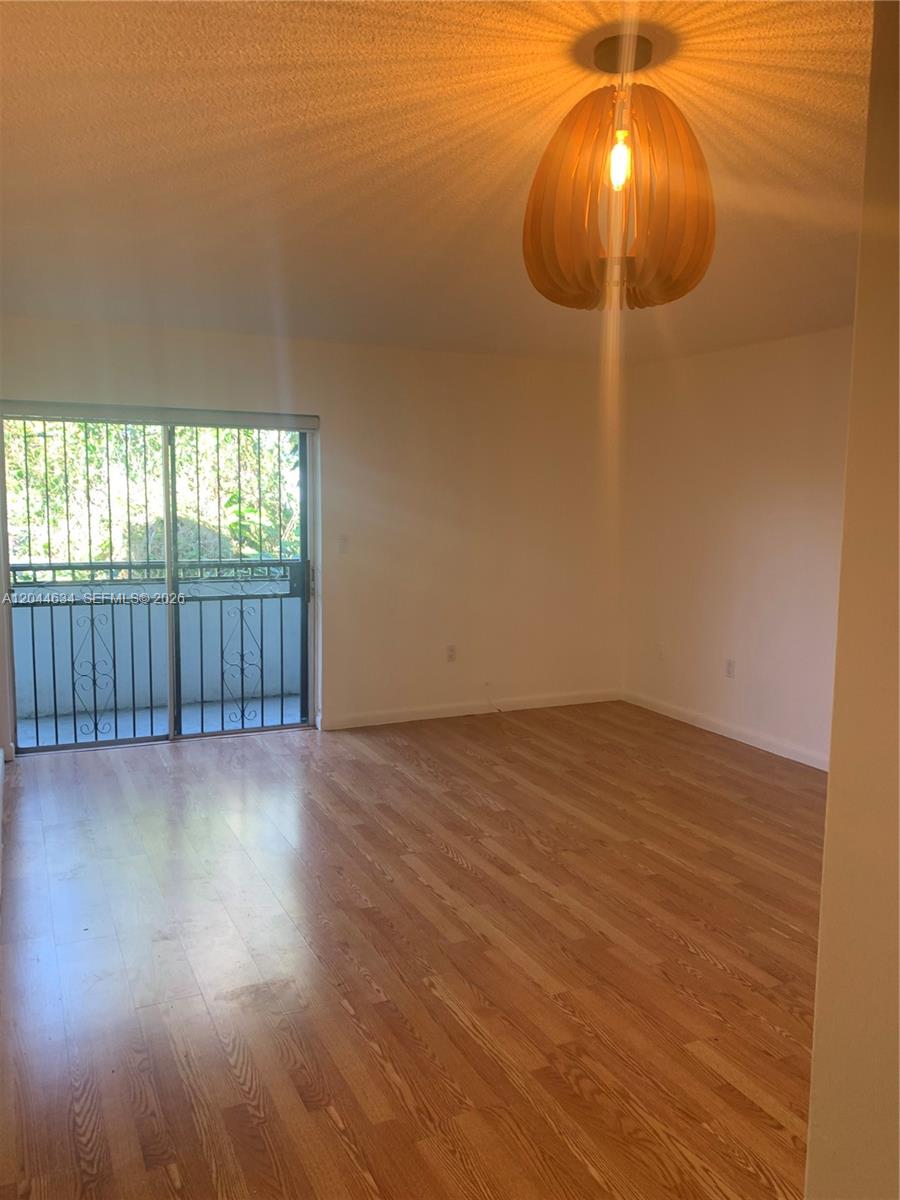 An empty room features light wood flooring, white walls, and a decorative wooden pendant light — 2460 SW 18th Ave # 1205, Miami FL 33145, MIAMI, FL
