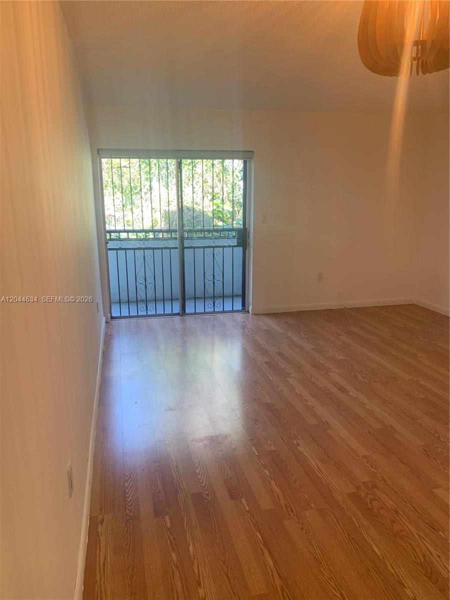 An empty room features light wood-look flooring, white walls, and a sliding glass balcony door — 2460 SW 18th Ave # 1205, Miami FL 33145, MIAMI, FL