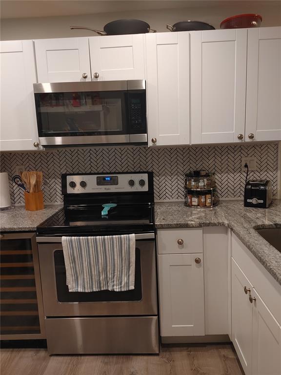 A kitchen features white cabinets, stainless steel appliances, granite countertops, and a herringbone tile backsplash — 6218 PALMA DEL MAR BOULEVARD S UNIT 213, ST PETERSBURG, FL