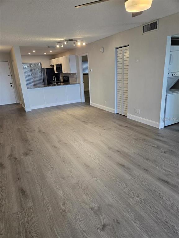 An open-concept living area features light wood-look flooring, a kitchen with white cabinets, and laundry — 6218 PALMA DEL MAR BOULEVARD S UNIT 213, ST PETERSBURG, FL