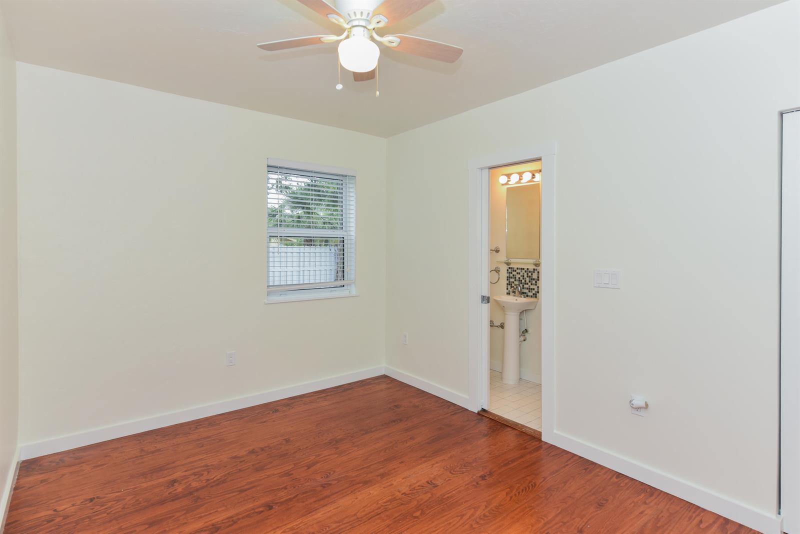 A bedroom features a bed with green accents, two nightstands, and two windows — 717 2nd Ave # 5, FL 33460, FL