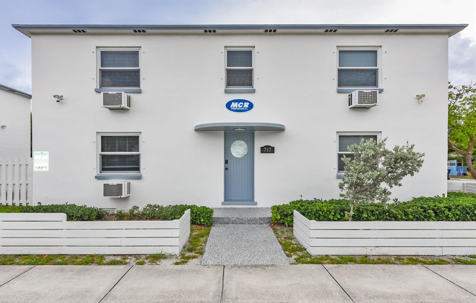 An empty bedroom features hardwood floors, a ceiling fan, two windows, and a wall-mounted air conditioner — 717 2nd Ave # 5, FL 33460, FL