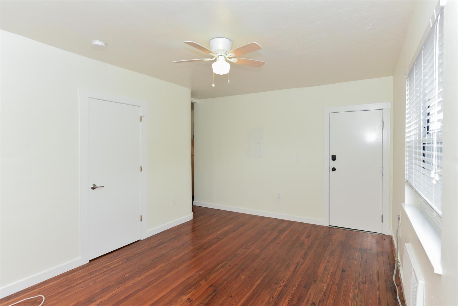 A bedroom with wood-look flooring, a ceiling fan, a window, and an attached half bathroom — 717 2nd Ave # 5, FL 33460, FL