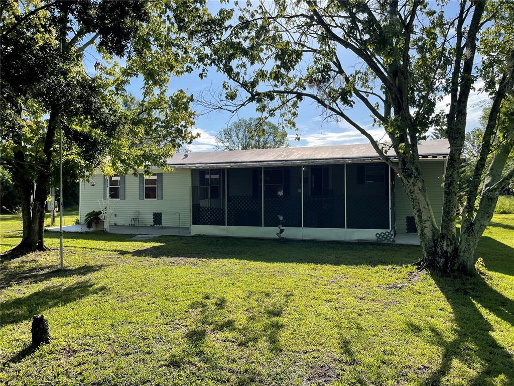 A single-story house with light siding and a screened-in porch sits on a grassy lot — 8929 HONEYWELL ROAD, GIBSONTON, FL