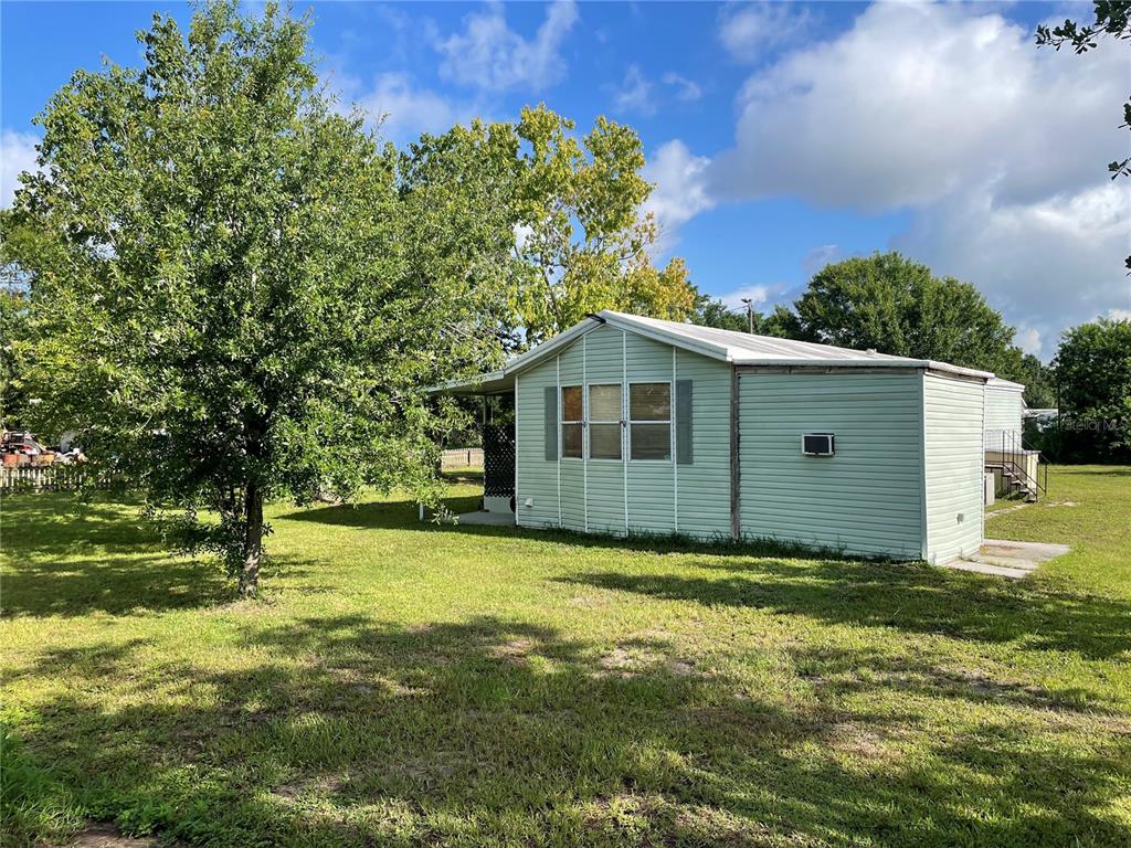 A light green mobile home sits on a grassy lot with a large tree — 8929 HONEYWELL ROAD, GIBSONTON, FL