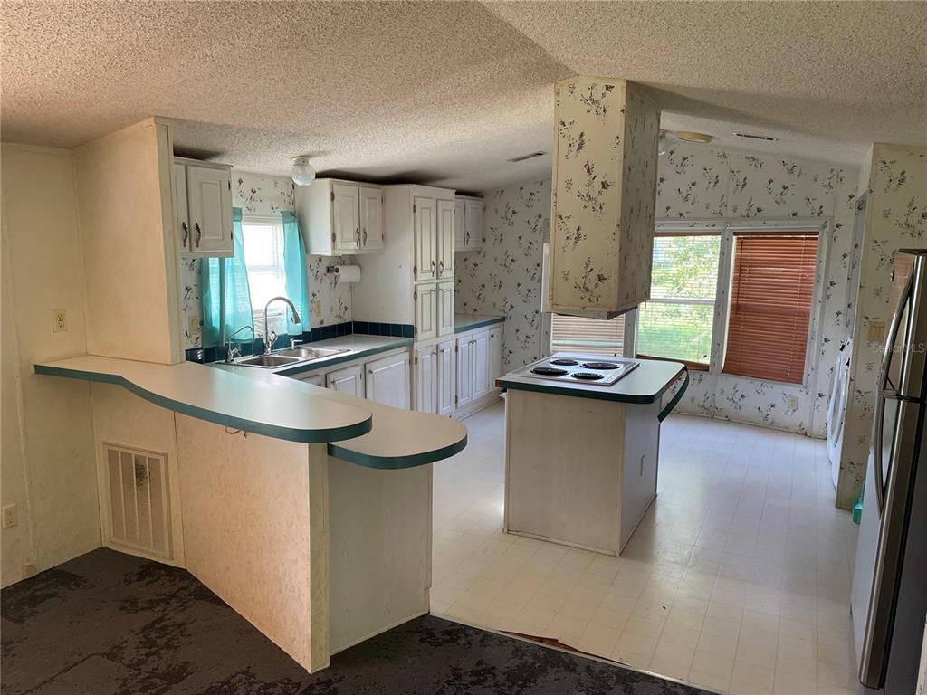 A kitchen with white cabinets, a central island cooktop, and floral wallpaper — 8929 HONEYWELL ROAD, GIBSONTON, FL