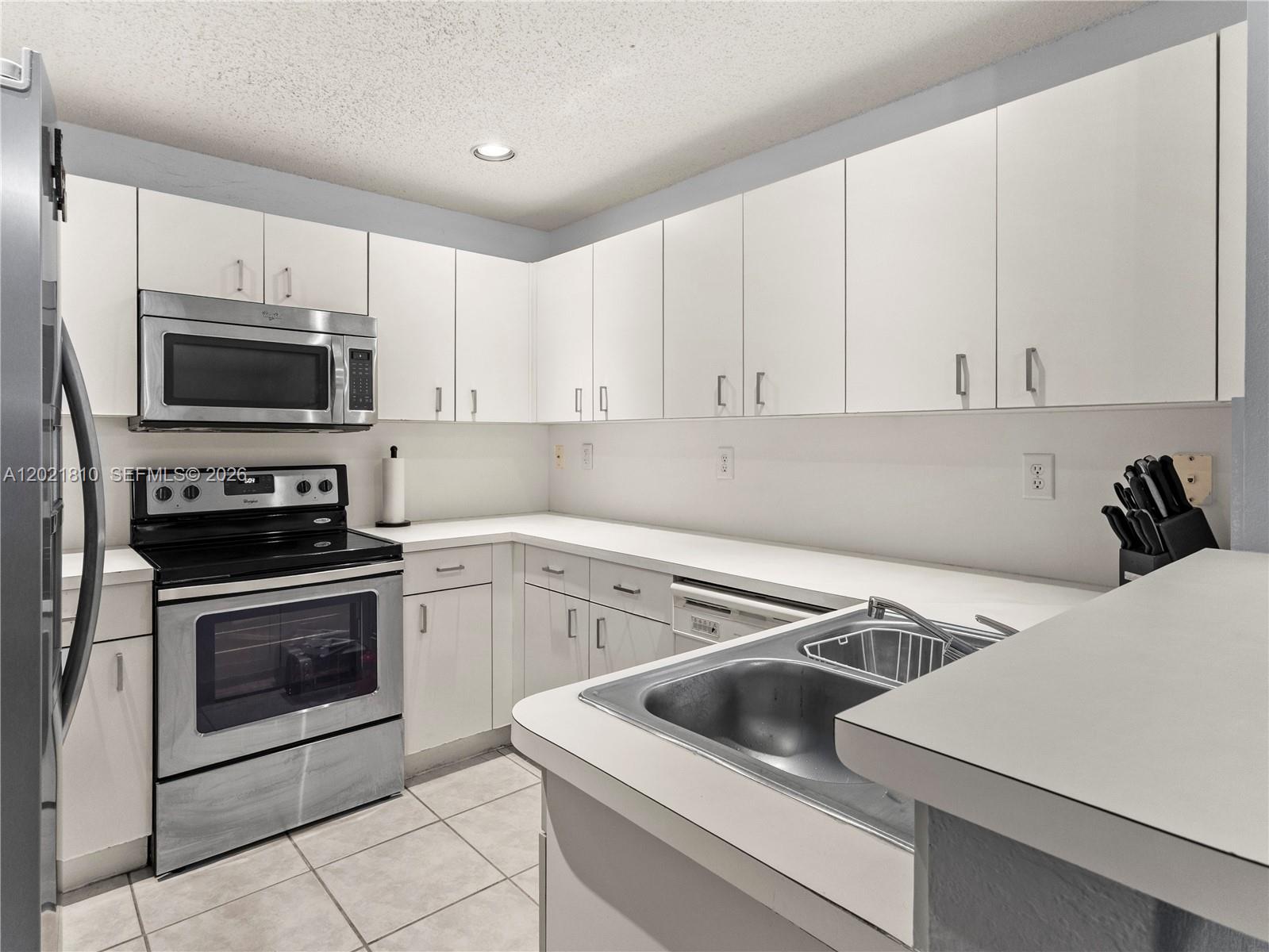 A kitchen features white cabinetry, stainless steel appliances, and a double-basin sink — 5033 NW 114th Ct, Doral FL 33178, DORAL, FL