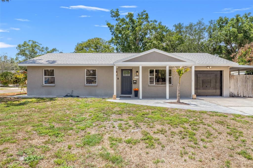 A single-story house with a gray stucco exterior, a dark front door, and a garage — 6802 CRESTHILL COURT, TAMPA, FL