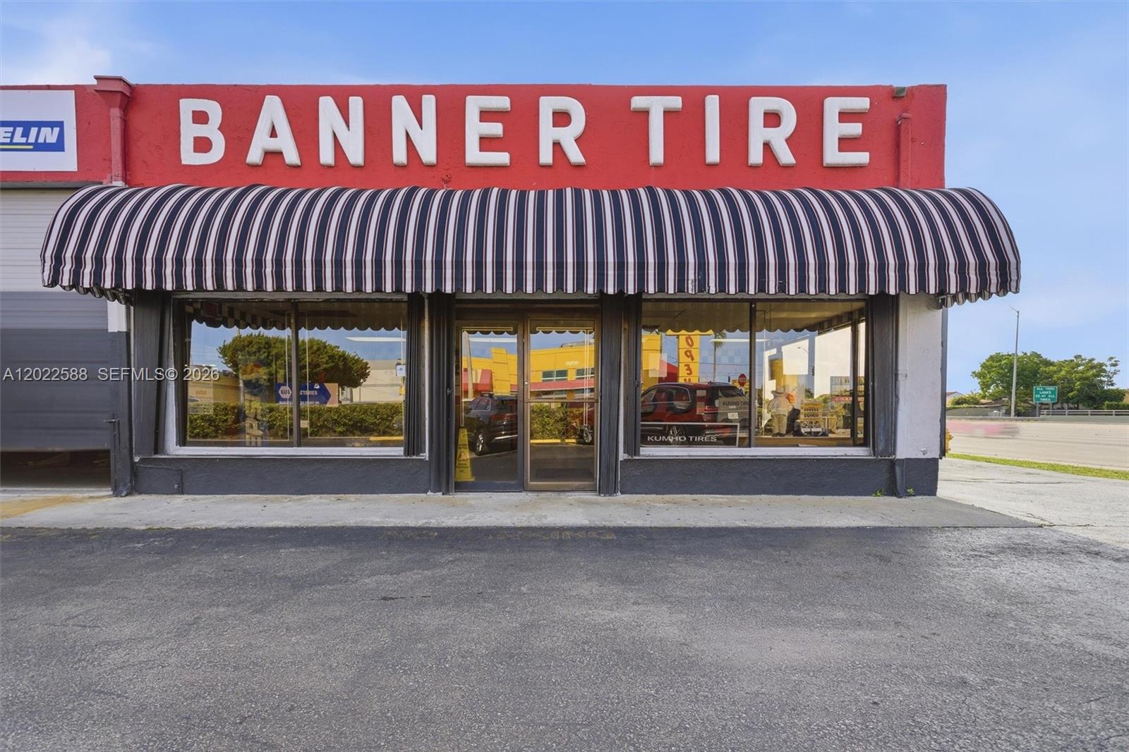 The exterior of a commercial tire shop features a red sign, striped awning, and glass storefront — 8730 SW 8th St, Miami FL 33174, MIAMI, FL