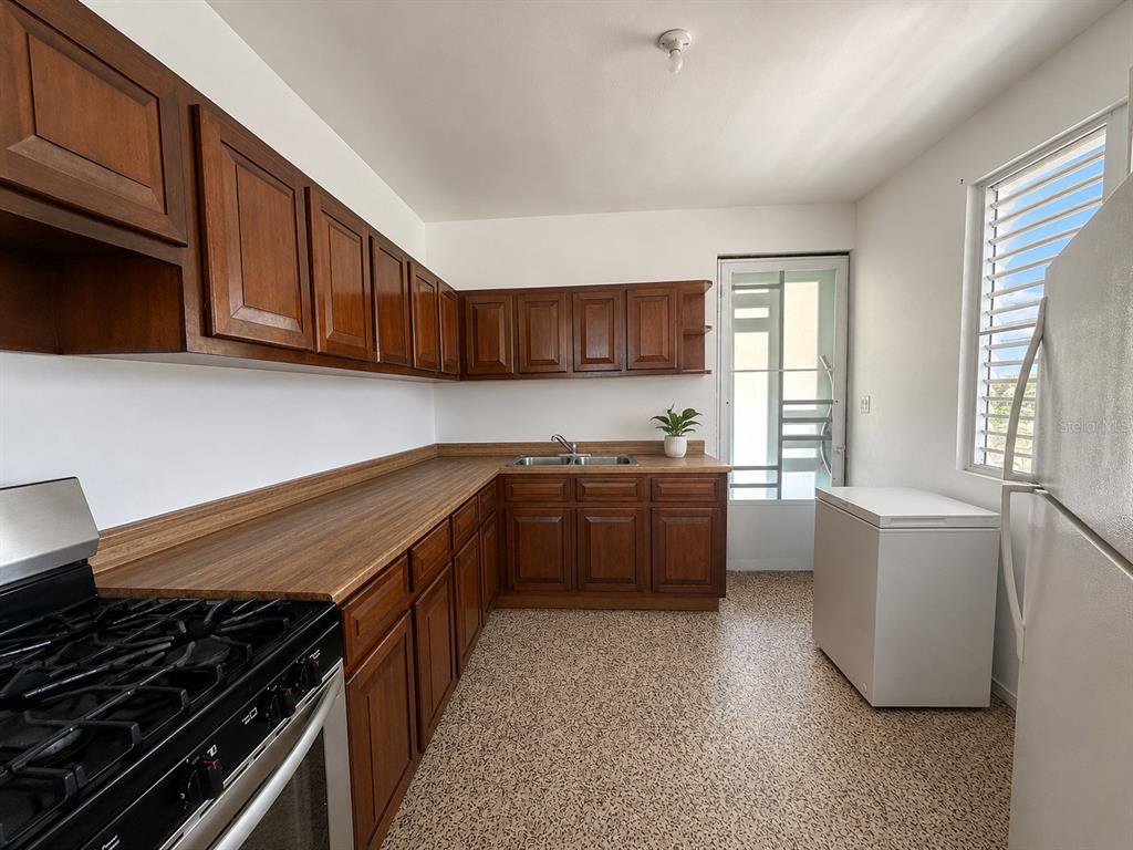 A kitchen features wood cabinets, a long laminate countertop, a gas stove, and a freezer — . SR 975 KM.1.6 LAS CALDERONAS, CEIBA, PR