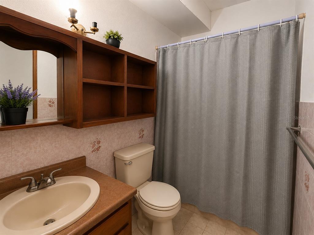A bathroom features a wooden vanity with a sink, open shelving, and a shower curtain — . SR 975 KM.1.6 LAS CALDERONAS, CEIBA, PR