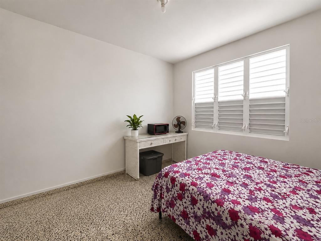 A bedroom with a floral bedspread, a white desk, and light-colored terrazzo flooring — . SR 975 KM.1.6 LAS CALDERONAS, CEIBA, PR