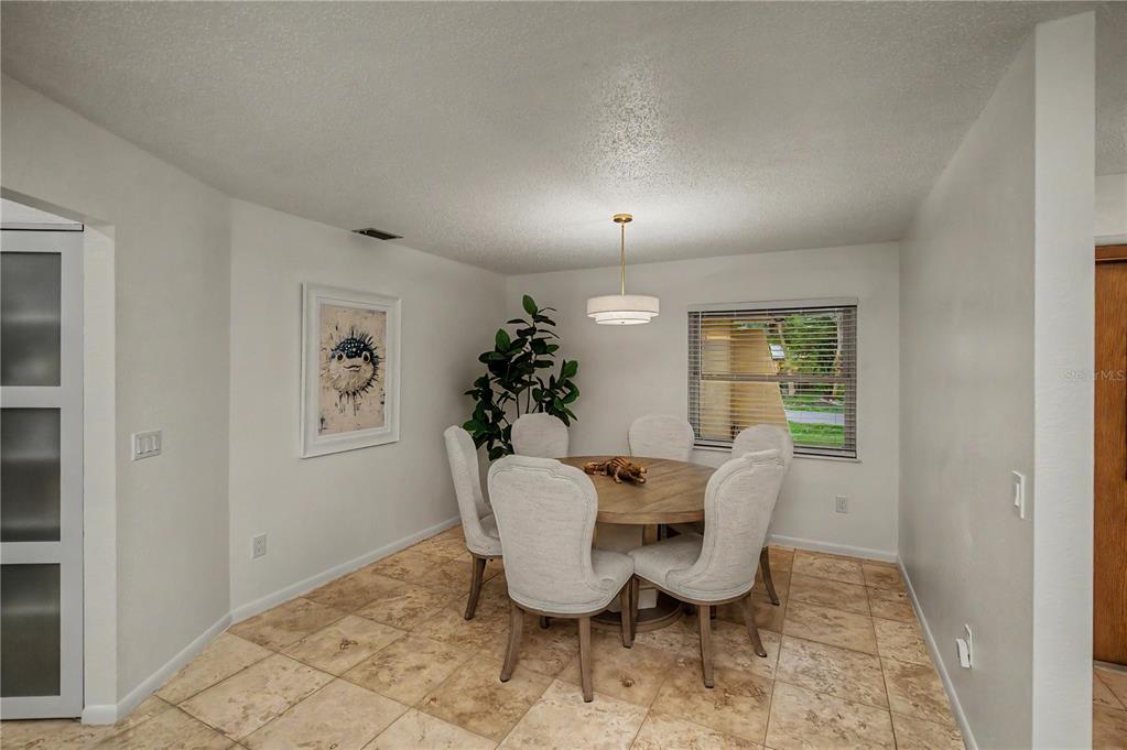 An entryway with tile flooring, a wooden front door, and a view into a dining area — 2199 BENDWAY DRIVE, PORT CHARLOTTE, FL