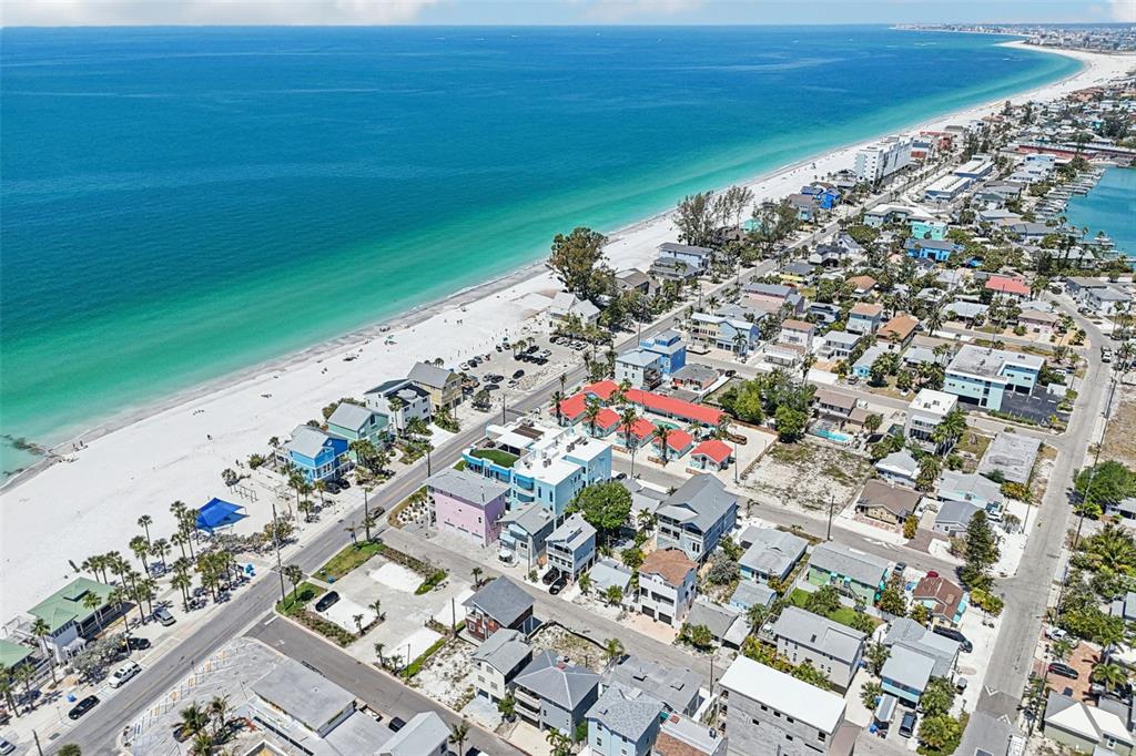 An aerial view shows a coastal neighborhood with colorful houses situated along a sandy beach — 23 80TH AVENUE, TREASURE ISLAND, FL