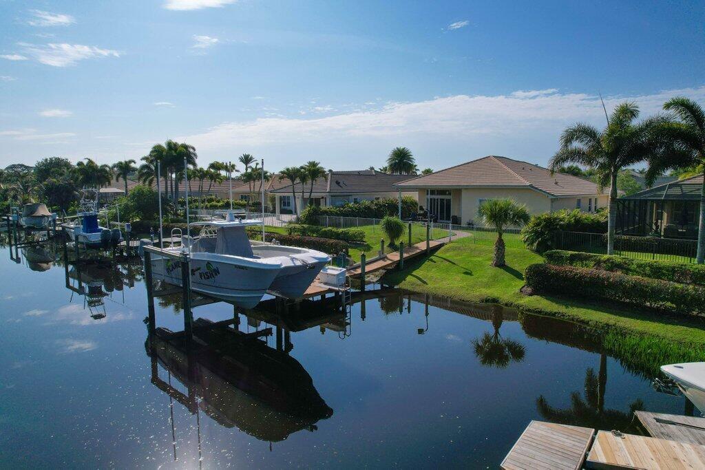 An aerial view of a canal-front home with a boat lift and palm trees — 479 SW Lost River Road, Stuart FL 34997, STUART, FL