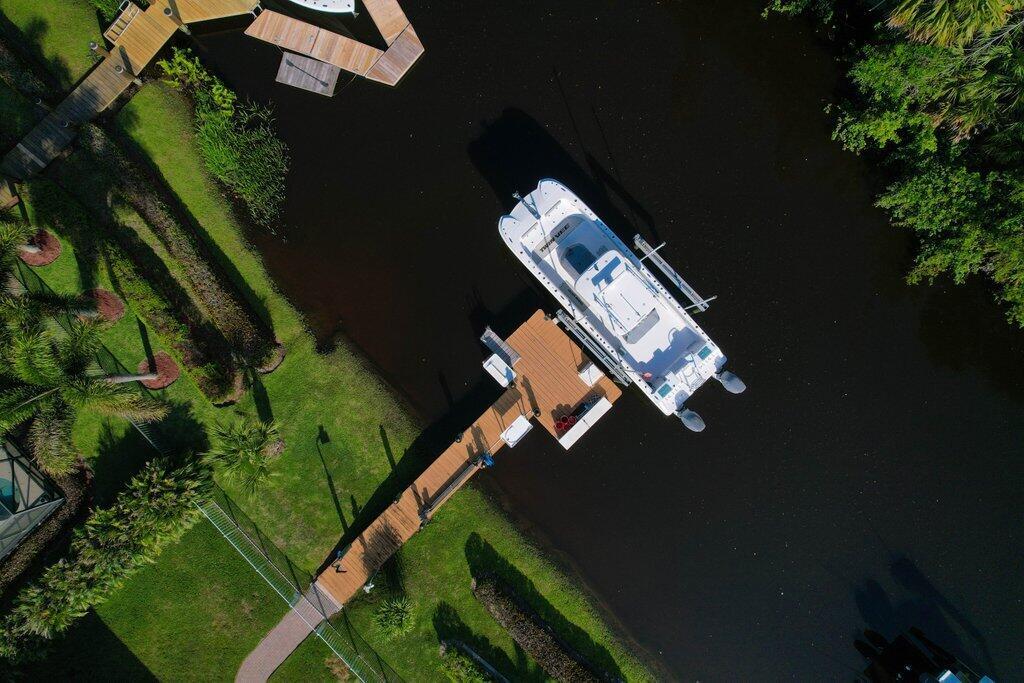 An aerial view shows a white boat docked at a wooden pier in a canal — 479 SW Lost River Road, Stuart FL 34997, STUART, FL