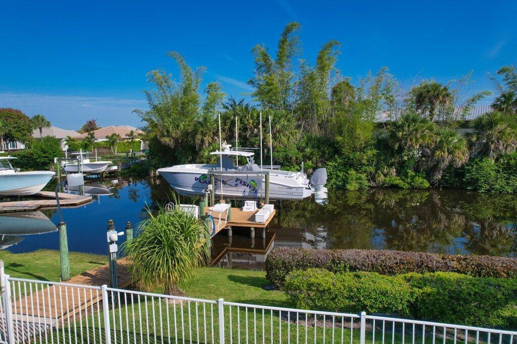 A white boat is docked in a canal behind a house with a white fence — 479 SW Lost River Road, Stuart FL 34997, STUART, FL