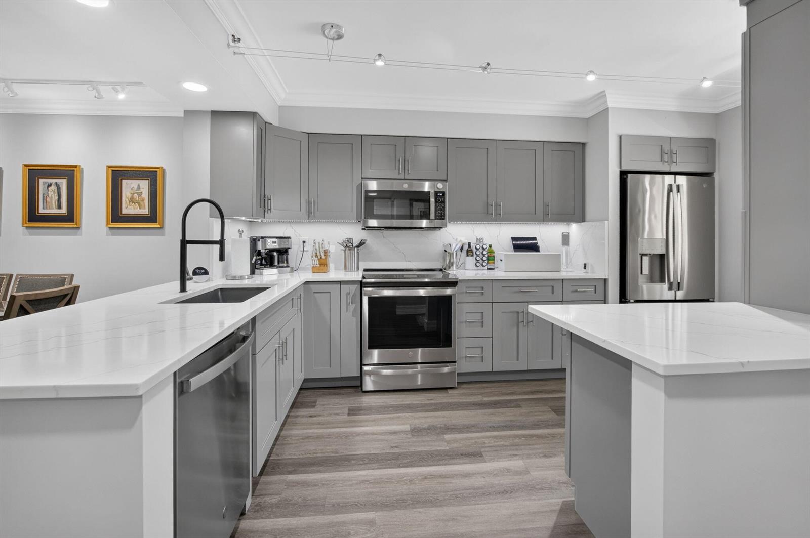 A modern kitchen features gray cabinets, stainless steel appliances, and white quartz countertops — 14111 Royal Vista Drive # 207, Delray Beach FL 33484, DELRAY BEACH, FL