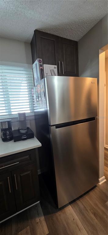 A stainless steel refrigerator stands next to dark wood cabinets and a white countertop — 39132 COUNTY ROAD 54 UNIT 2048, ZEPHYRHILLS, FL