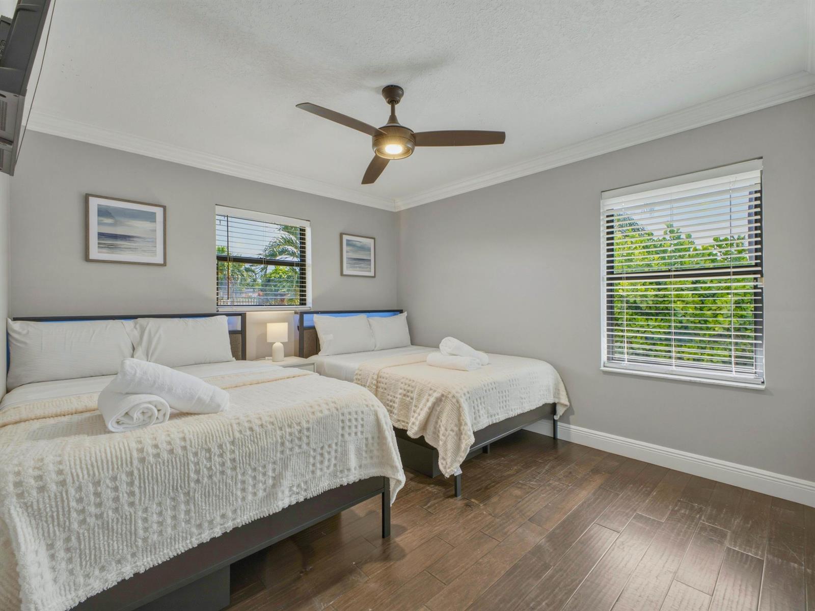 A bedroom features two beds with white bedding, dark wood flooring, and a ceiling fan — 1127 Sea Pines Way, Lantana FL 33462, LANTANA, FL