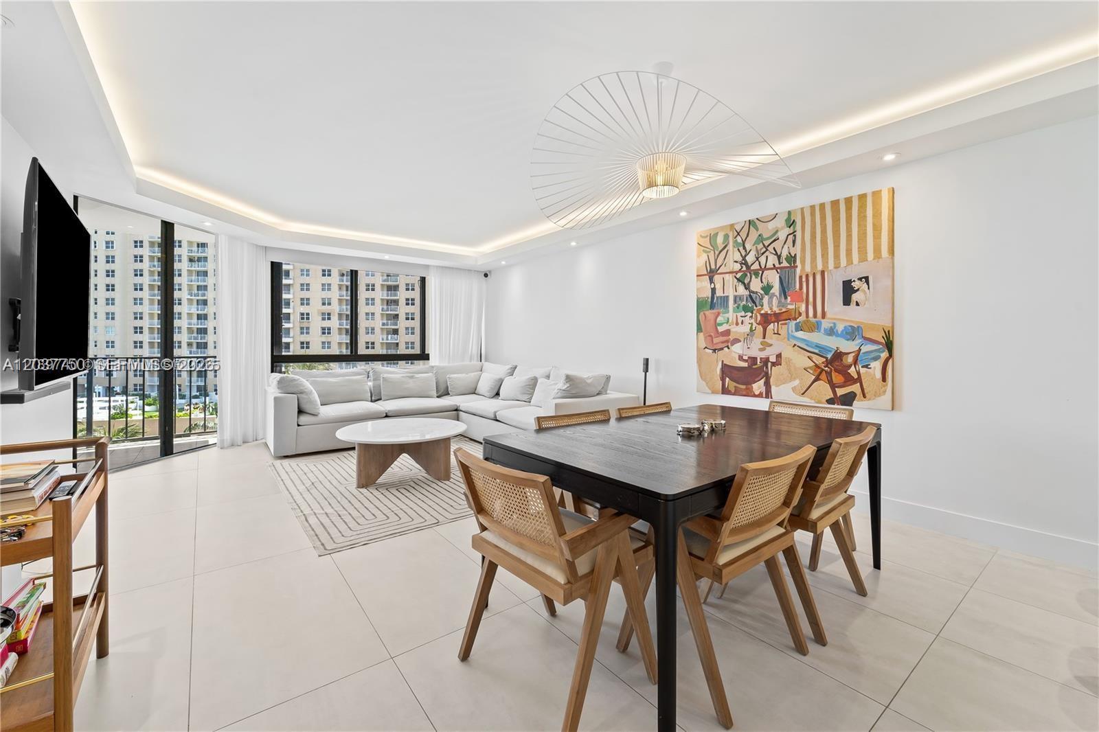 A bright open-concept living and dining area features a large sectional, wooden chairs, and artwork — 520 Brickell Key Dr # A713, Miami FL 33131, MIAMI, FL