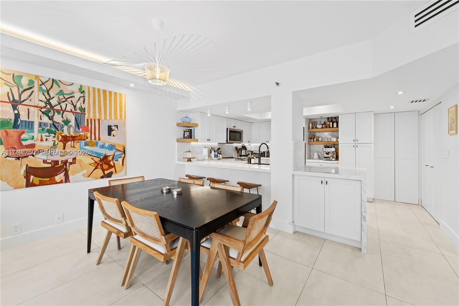A dining area with a dark table and cane chairs sits beside a white kitchen — 520 Brickell Key Dr # A713, Miami FL 33131, MIAMI, FL