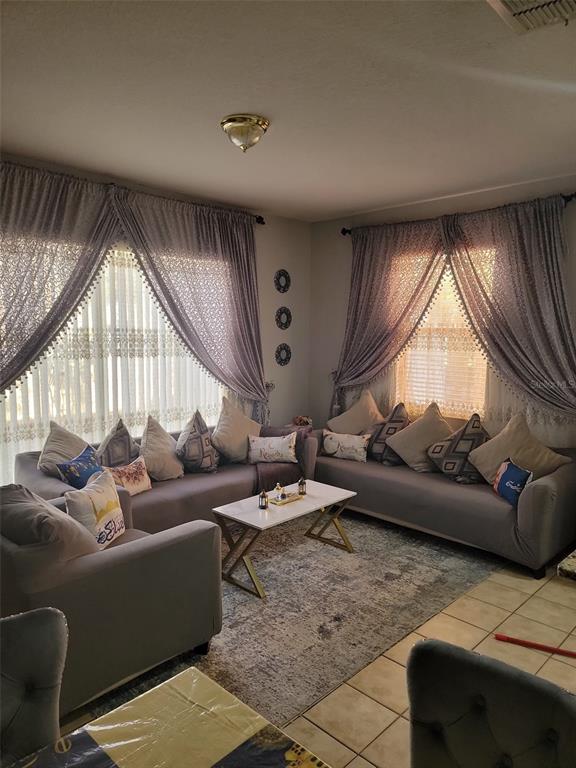 A living room features gray sofas, a white coffee table, and curtains over vertical blinds — 2682 MAYAGUANA STREET, KISSIMMEE, FL