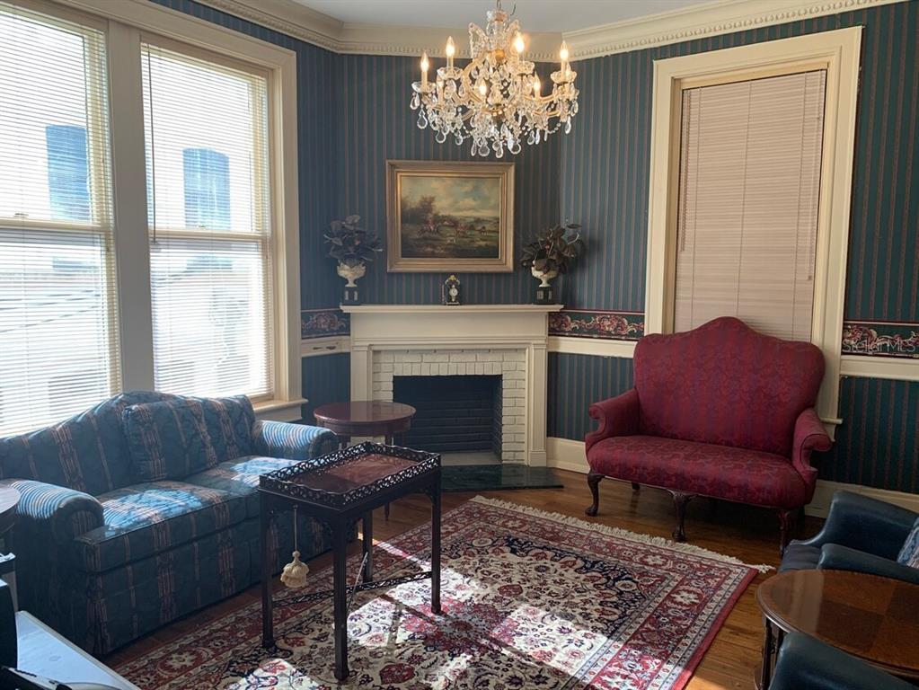 A formal living room features striped wallpaper, a fireplace, a crystal chandelier, and traditional furniture — 250 E PARK AVENUE, LAKE WALES, FL