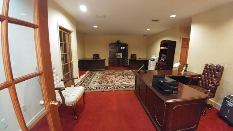 A home office features a red carpet, two wooden desks, and a large area rug — 250 E PARK AVENUE, LAKE WALES, FL