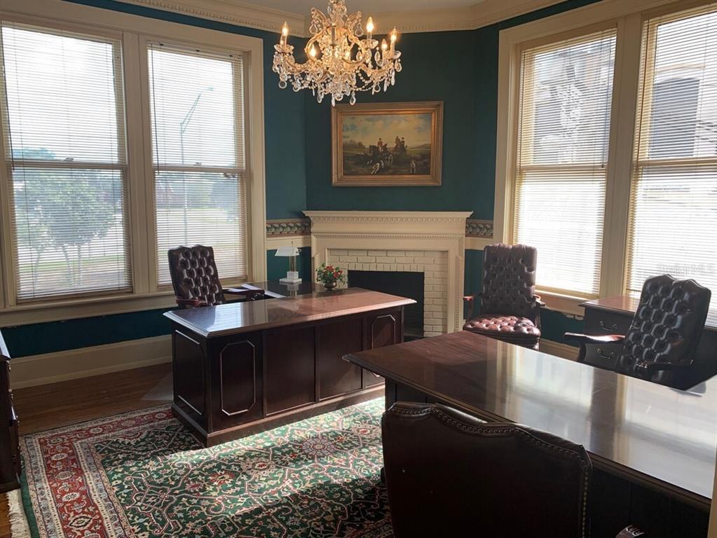 A home office features two dark wood desks, leather chairs, a fireplace, and a chandelier — 250 E PARK AVENUE, LAKE WALES, FL