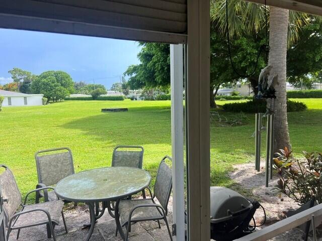 A patio with a glass-top table and four chairs overlooks a large grassy yard — 5452 Poppy Place # B, Delray Beach FL 33484, DELRAY BEACH, FL