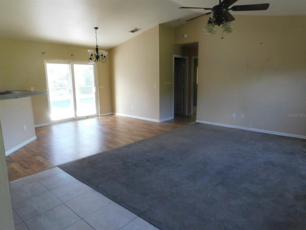 A living area features a carpeted section, wood-look flooring, a ceiling fan, and sliding doors — 2637 TISHMAN AVENUE, NORTH PORT, FL