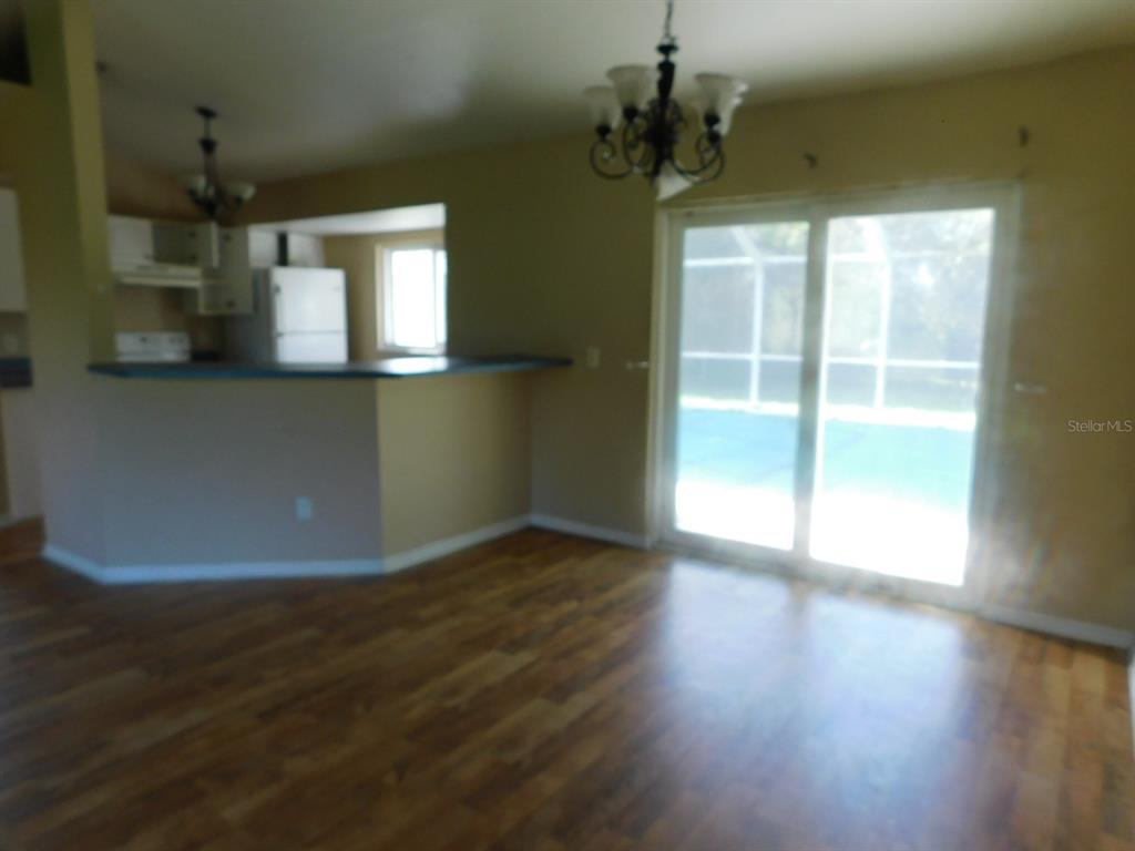 A dining area with wood-look flooring, a chandelier, and sliding glass doors to a pool — 2637 TISHMAN AVENUE, NORTH PORT, FL