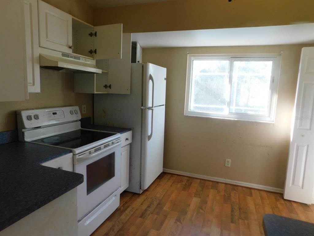 A kitchen features white cabinets, a white stove, a white refrigerator, and wood-look flooring — 2637 TISHMAN AVENUE, NORTH PORT, FL