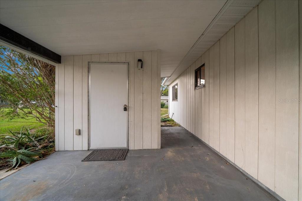 A covered concrete patio features vertical white siding and a single exterior door — 9200 SW 103RD LANE, OCALA, FL