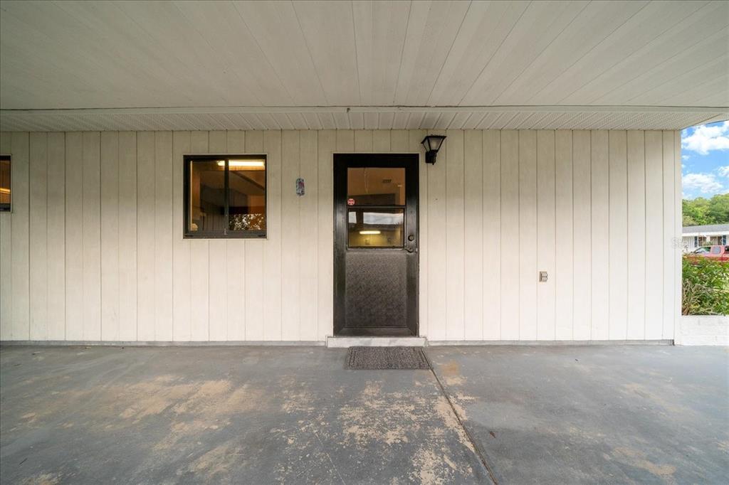 A covered concrete patio leads to a black storm door and a single window — 9200 SW 103RD LANE, OCALA, FL