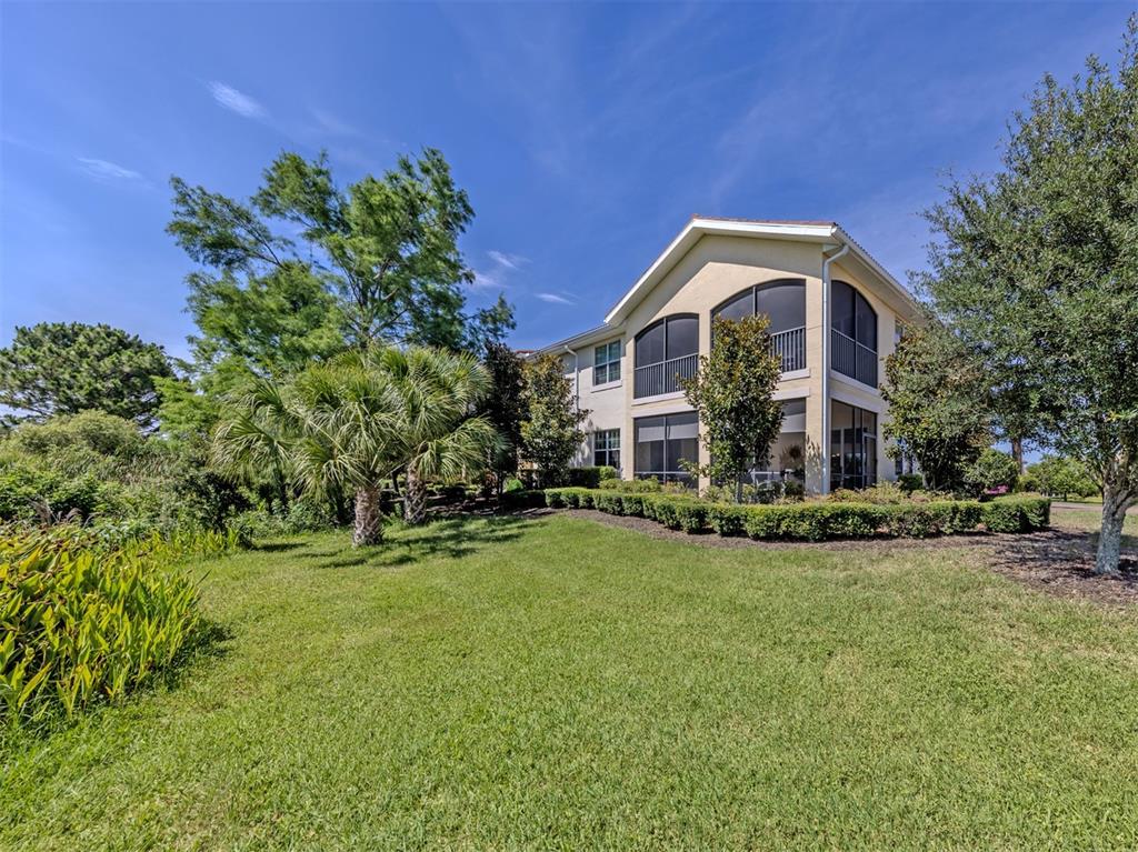 A multi-story residential building features screened-in balconies and is surrounded by a landscaped lawn — 194 BELLA VISTA TERRACE UNIT 26A, NORTH VENICE, FL