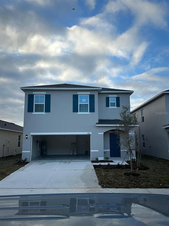A two-story house with a gray exterior, blue shutters, and an open two-car garage — 687 PARK PLACE BOULEVARD, DAVENPORT, FL