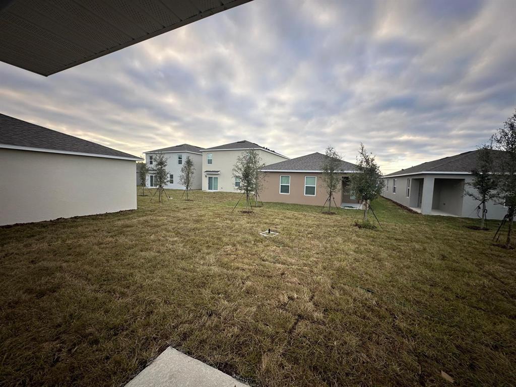 A view of a grassy backyard surrounded by several newly constructed suburban houses — 687 PARK PLACE BOULEVARD, DAVENPORT, FL
