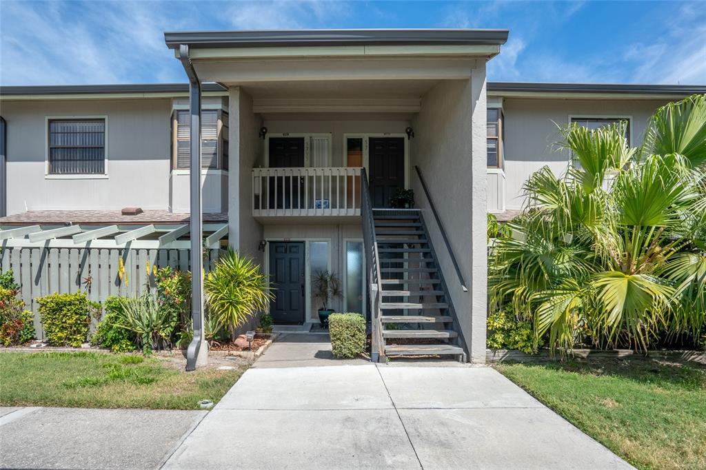A two-story apartment building exterior features a concrete walkway, stairs, and a second-floor balcony — 5797 SUMMER SIDE LANE UNIT 7A, SARASOTA, FL
