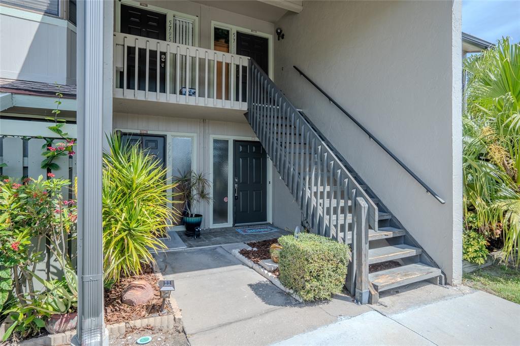 An exterior view of a two-story apartment building with a wooden staircase and balcony — 5797 SUMMER SIDE LANE UNIT 7A, SARASOTA, FL