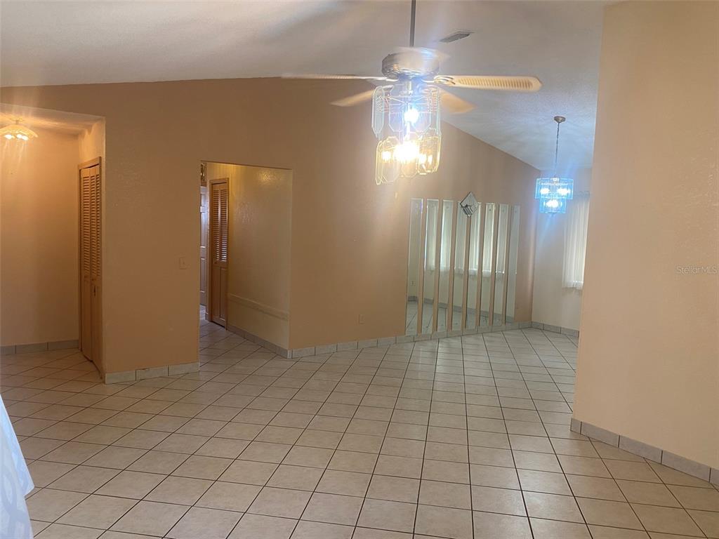 A tiled living area features a ceiling fan, mirrored wall panels, and a dining light fixture — 1101 STILLWATER AVENUE, DELTONA, FL