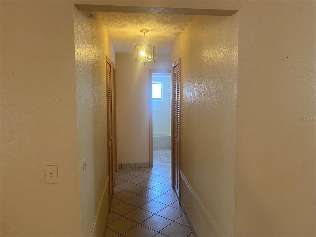 A hallway with tiled floors leads to a bathroom with a tub and shower — 1101 STILLWATER AVENUE, DELTONA, FL