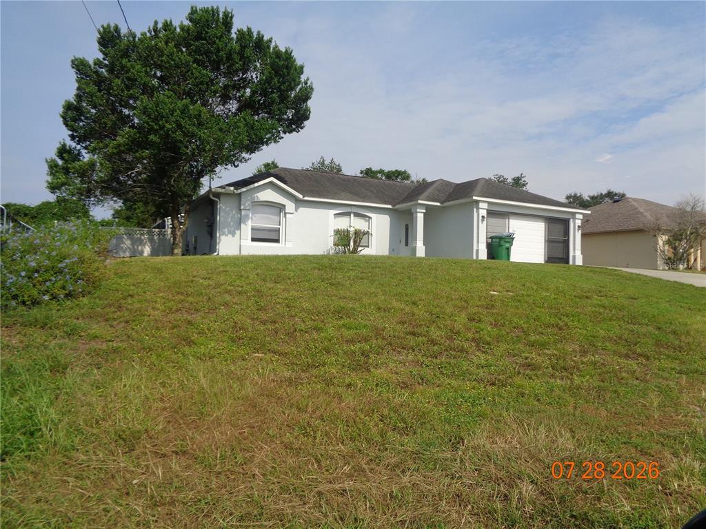 A single-story house with a light-colored exterior sits on a grassy, sloped lot — 2610 GROVELAND AVENUE, DELTONA, FL