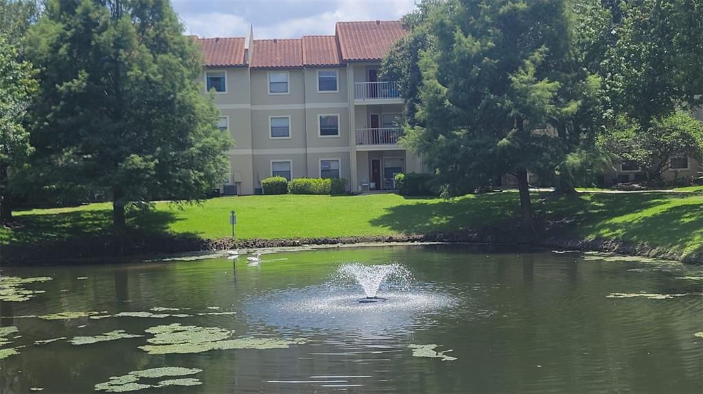 A pond with a fountain sits in front of a multi-story apartment building — 3008 PARKWAY BOULEVARD UNIT 107, KISSIMMEE, FL